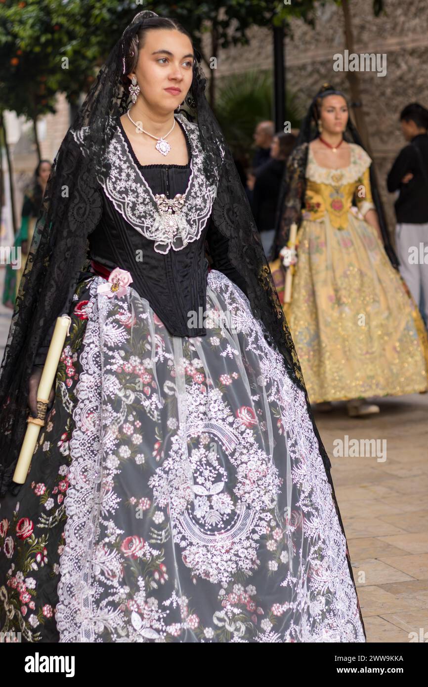 Valencianische Tradition in voller Darstellung: Die festliche Kleidung einer Fallera. Das Kleid, eine lebendige Leinwand der Geschichte, zieht mit Stolz und Elend durch die Straßen von Gandia Stockfoto