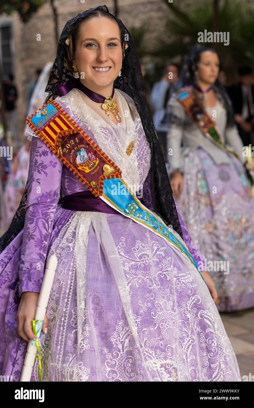 Valencianische Vibrance in Gandias Festlichkeiten: Das Kostüm einer Fallera im Fokus. Das detailreiche Ensemble spiegelt das temperamentvolle Wesen der Fallas wider Stockfoto