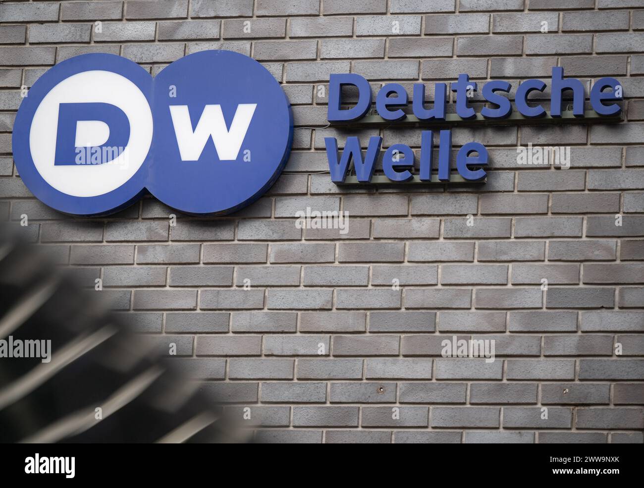 Berlin, Deutschland. März 2024. Das Logo der Deutschen Welle ist am Eingang des Hauptsitzes des Senders in der Hauptstadt zu sehen. DW ist eine Einrichtung des öffentlichen Rechts und arbeitet in drei Medien: Fernsehen, Radio und Internet. Quelle: Monika Skolimowska/dpa/Alamy Live News Stockfoto