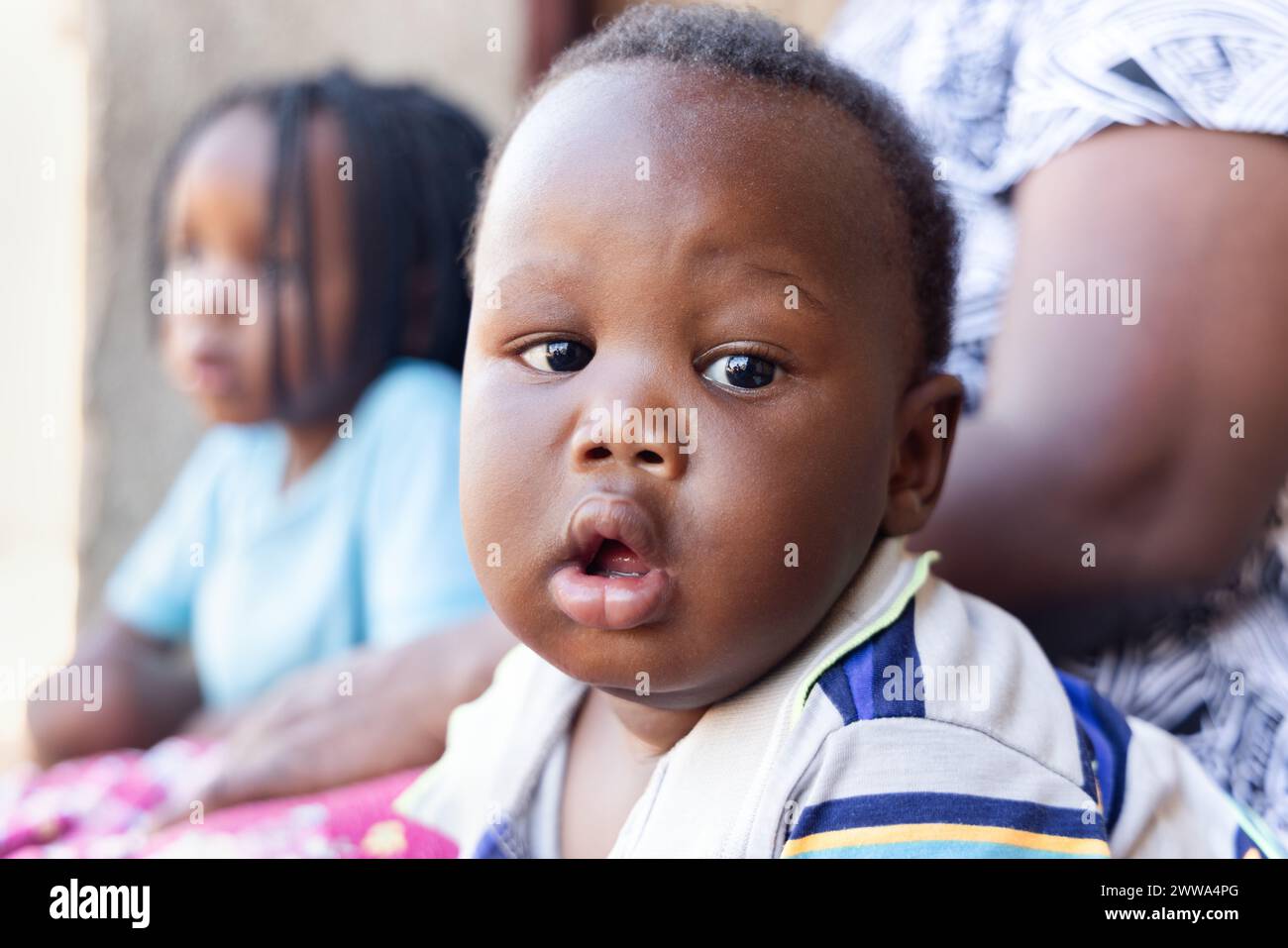 Village african Baby, zu Hause, stehend vor dem Haus auf der Veranda mit seiner Schwester Stockfoto