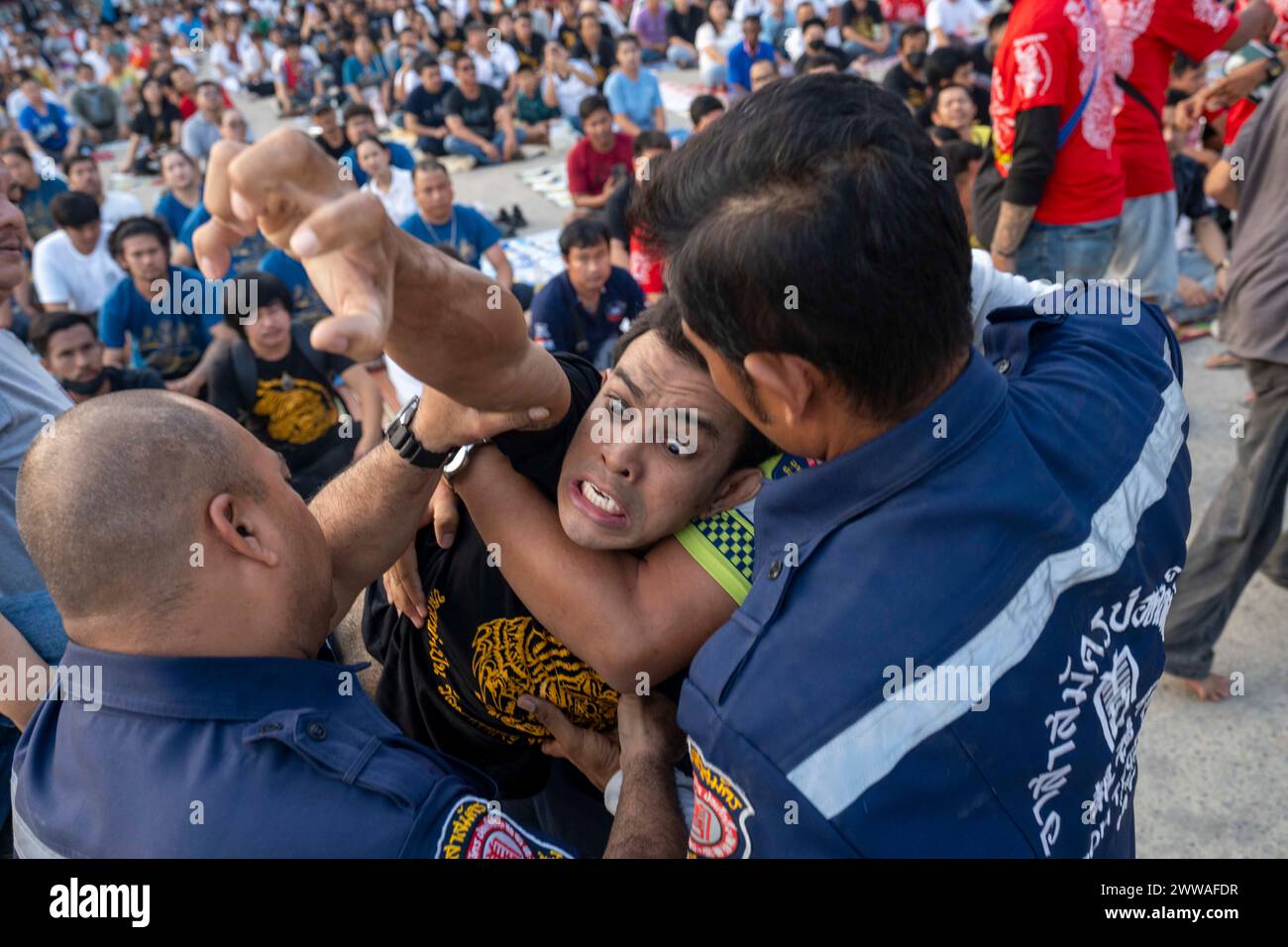 Nakhon Pathom, Thailand. März 2024. Gläubige, die heilige sak Yant Tattoos hatten, fallen während der jährlichen Wai Kru Zeremonie in Wat Bang Phra in Nakhon Pathom, Thailand in Besitz und gewaltsam in Richtung des Tempels. Wat Bang Phra Tempel, 40 km von der thailändischen Hauptstadt Bangkok entfernt, findet einmal im Jahr die Wai Gru Zeremonie statt. Der Name des Tempels wird übersetzt als Kloster des Flussufers Buddha Bild. Sak Yant Tätowierungen sind hochstilisierte Tätowierungen buddhistischer Gebete und religiöser Symbole, die den Gläubigen, die sie auf ihren Körper legen, einen besonderen Schutz und andere Vorteile bieten. Stockfoto