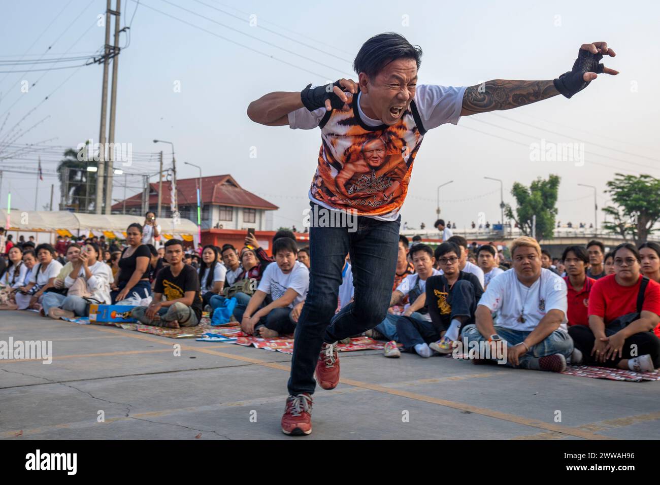 Nakhon Pathom, Thailand. März 2024. Gläubige, die heilige sak Yant Tattoos hatten, fallen während der jährlichen Wai Kru Zeremonie in Wat Bang Phra in Nakhon Pathom, Thailand in Besitz und gewaltsam in Richtung des Tempels. Wat Bang Phra Tempel, 40 km von der thailändischen Hauptstadt Bangkok entfernt, findet einmal im Jahr die Wai Gru Zeremonie statt. Der Name des Tempels wird übersetzt als Kloster des Flussufers Buddha Bild. Sak Yant Tätowierungen sind hochstilisierte Tätowierungen buddhistischer Gebete und religiöser Symbole, die den Gläubigen, die sie auf ihren Körper legen, einen besonderen Schutz und andere Vorteile bieten. Stockfoto