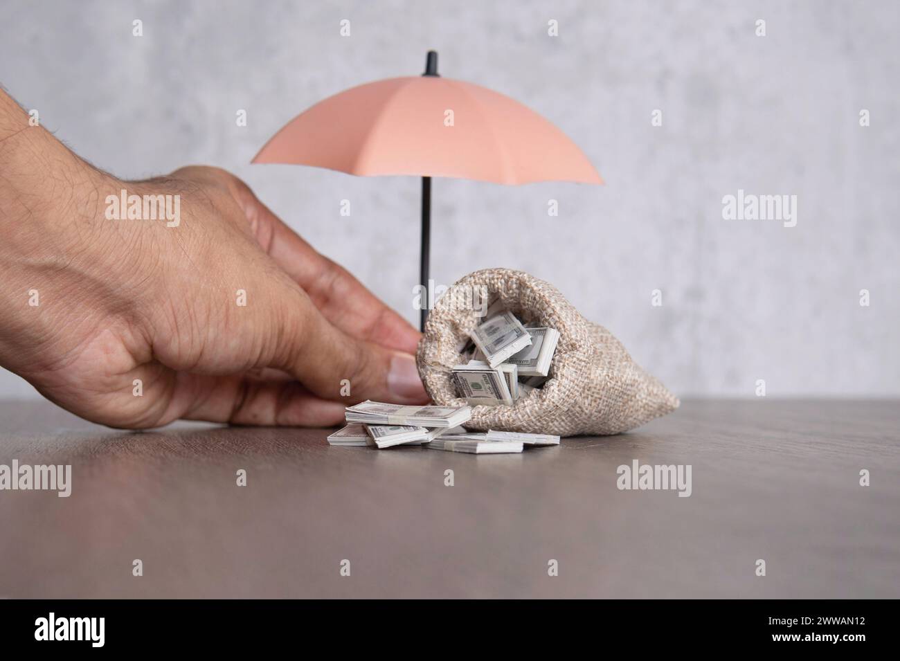 Einen Handschirm halten, der eine Tasche voller Geld schützt. Finanzielle Sicherheit, Einkommensschutzversicherungskonzept. Stockfoto