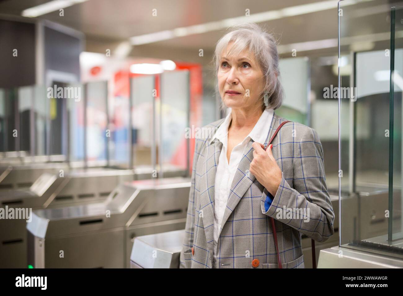 Reife Dame geht durch die Schranken in der U-Bahn-Station Stockfoto