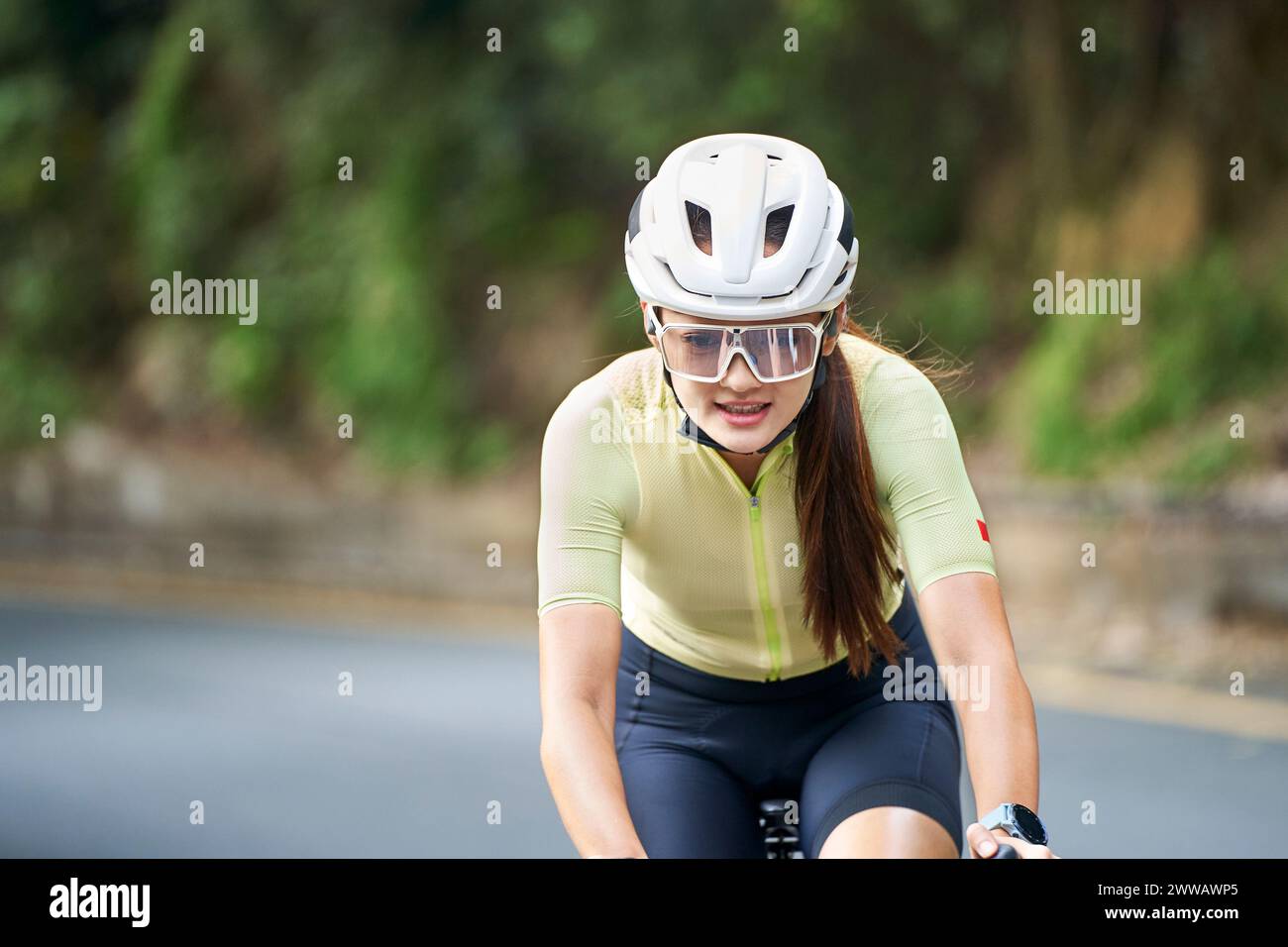 Junge asiatische Frau mit Helm und Fahrrad auf der Landstraße Stockfoto