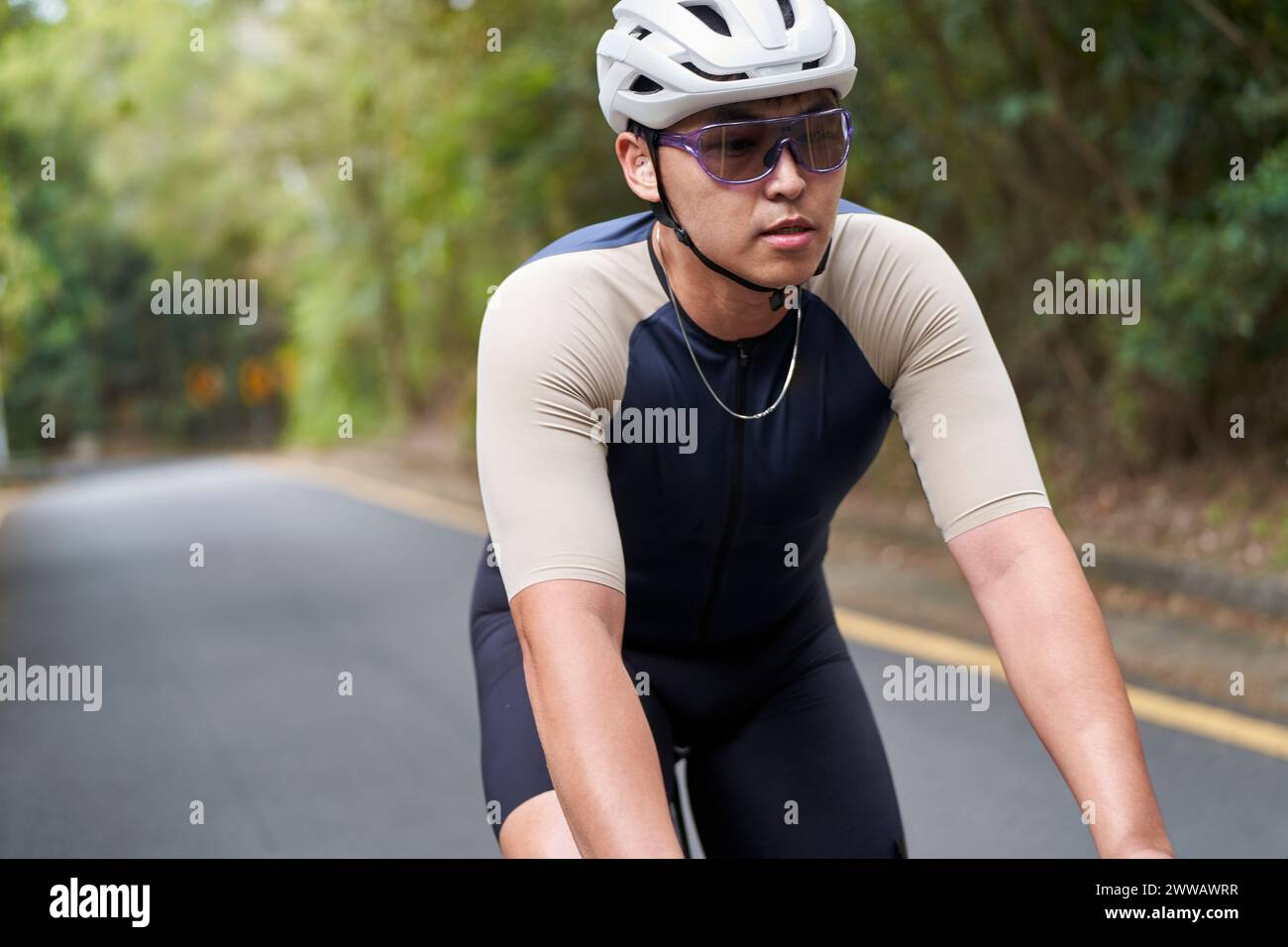 Junger asiatischer Mann, männlicher Radfahrer, der draußen auf der Landstraße Fahrrad fährt Stockfoto