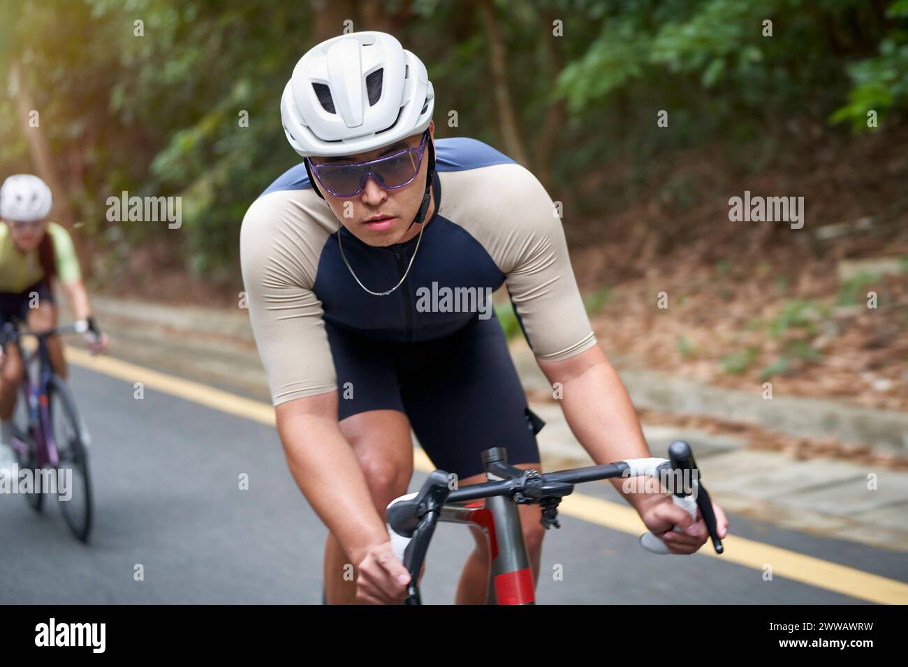 Junger asiatischer Mann, männlicher Radfahrer, der draußen auf der Landstraße Fahrrad fährt Stockfoto