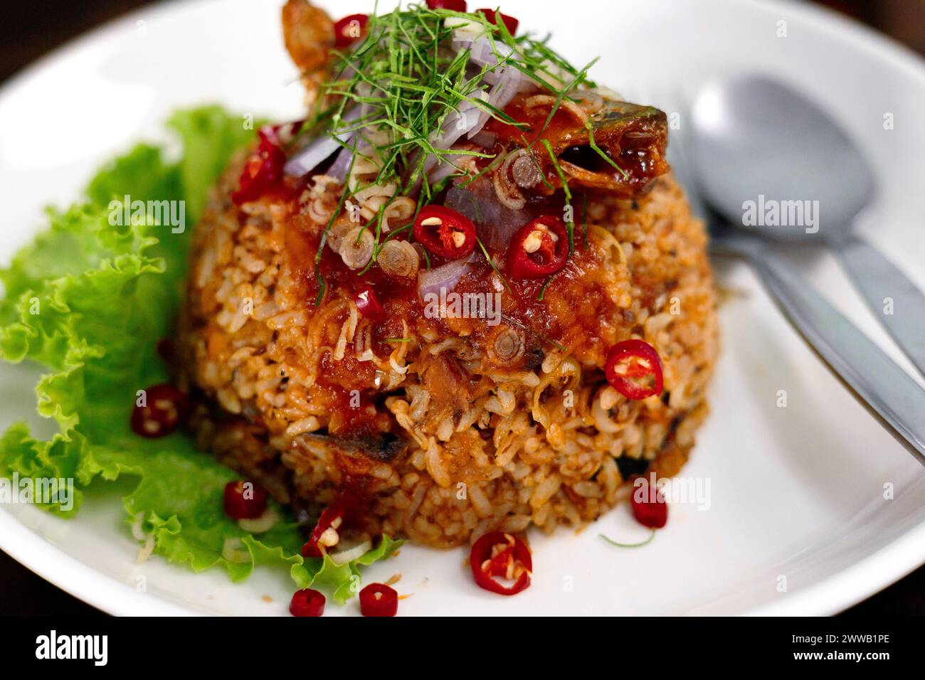 Thailändisches Essen, gebratener Jasminreis mit Makrelen in der Dose in Tomatensauce, garniert mit roter Chili, roten Zwiebeln, Salat und Kaffir-Limettenblättern. Stockfoto