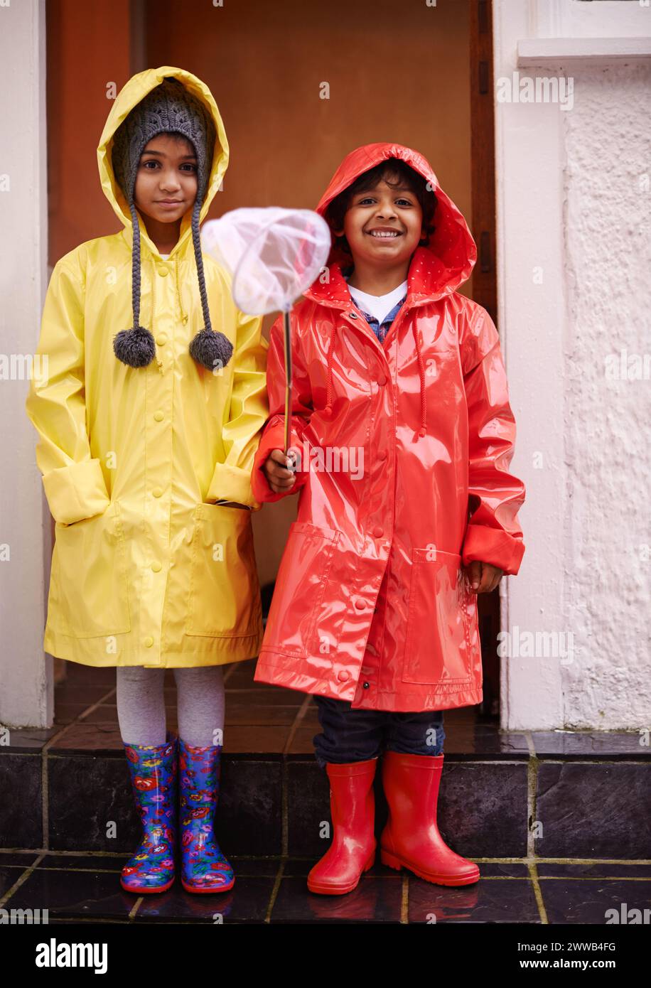 Kinder, Lächeln und Porträt mit Regenmantel für Outdoor, Abenteuer oder Regen für Erwachsene, Jugendliche und Winter. Indische Kinder und glücklich mit Stiefeln Stockfoto