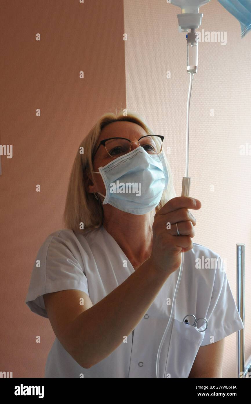 Eine Krankenschwester gibt einen Tropf auf einen Patienten in einem Krankenhaus. Stockfoto