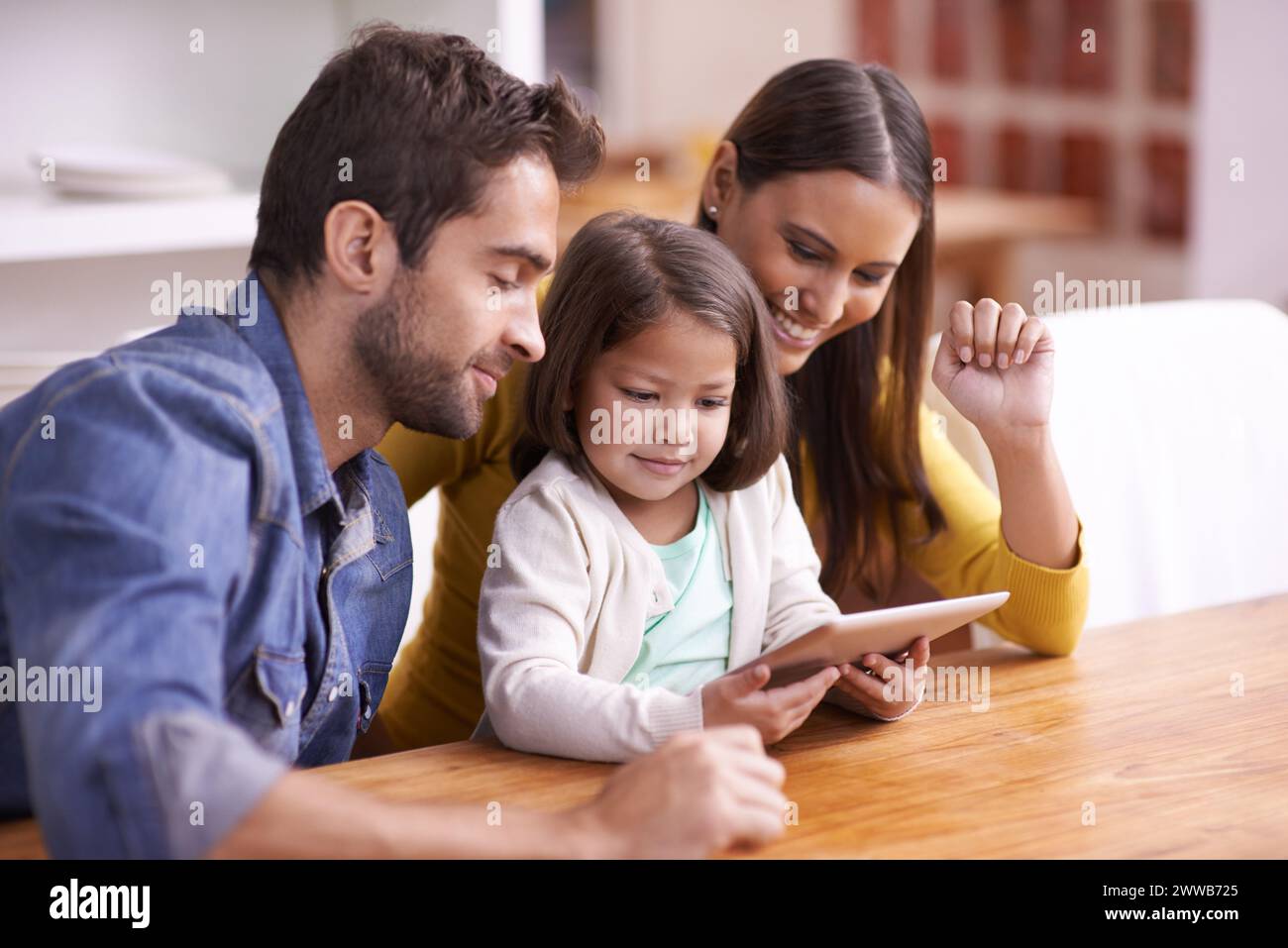 Mutter, Vater und Kind mit Tablet zum Unterrichten, Lernen und Unterstützung in Bildung mit Liebe am Tisch. E-Learning, digitale App und Eltern mit Mädchen Stockfoto