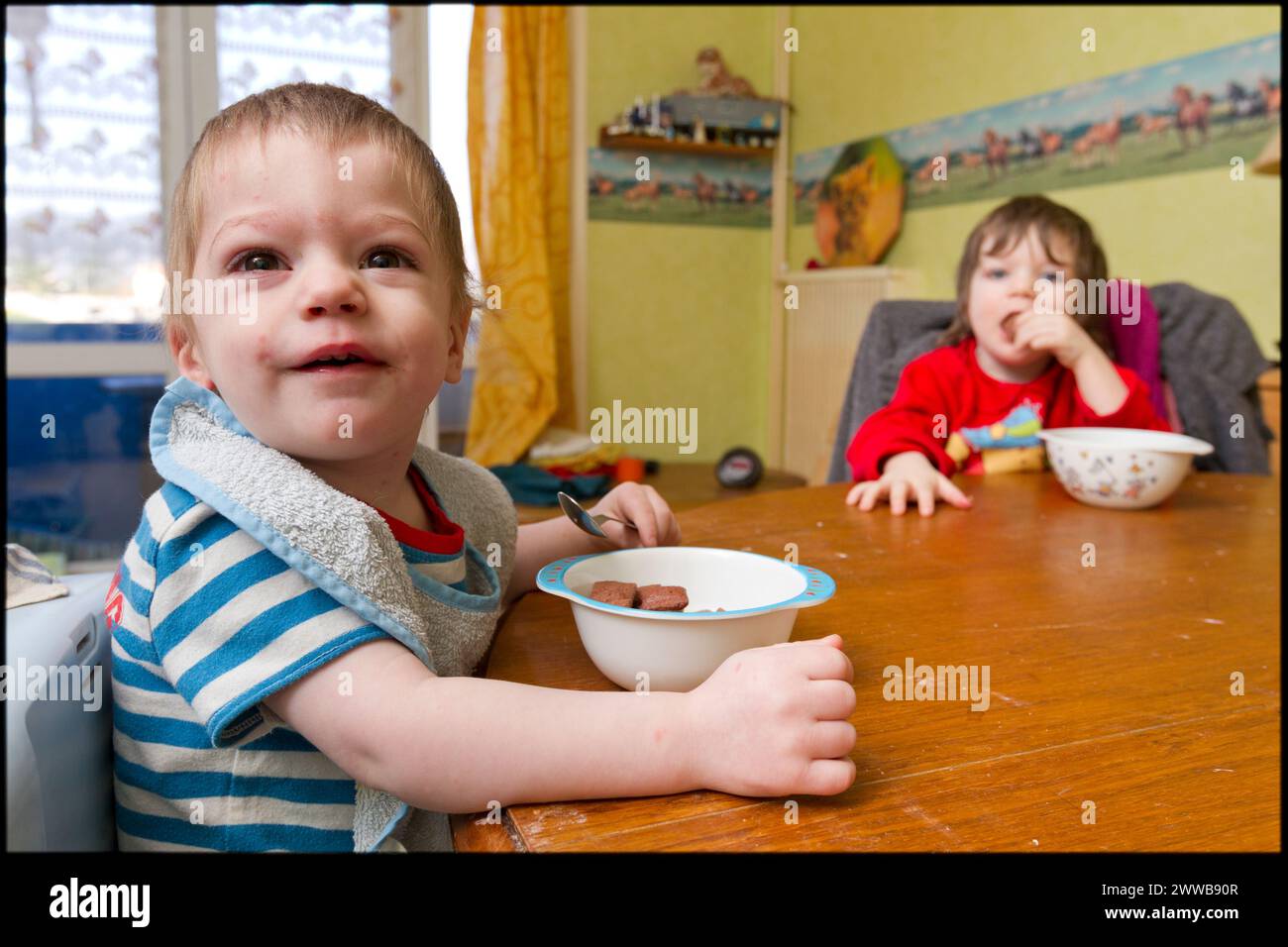 ASE - Kindersozialhilfe. Maxence, zwei Jahre alt, und seine Schwester Sarah, drei Jahre alt, frühstücken am Tisch. NUR FÜR REDAKTIONELLE ZWECKE. Stockfoto