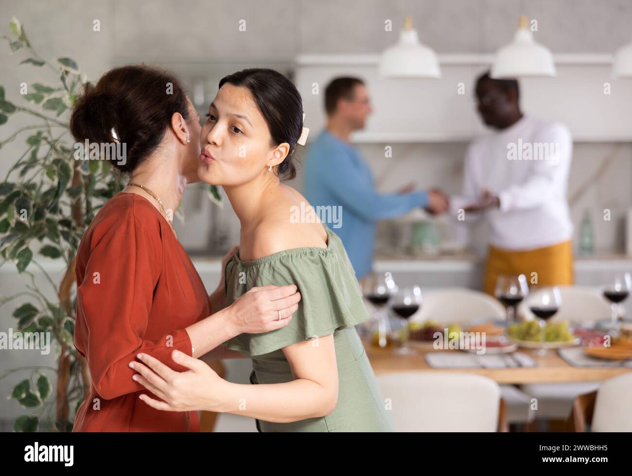 Lächelnde Frau gibt Begrüßungskuss an die beste bei einem informellen Abendessen Stockfoto