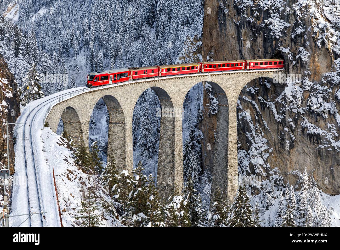 Filisur, Schweiz - 10. Januar 2024: Personenzug der Rhätischen Bahn am berühmten Landwasserviadukt an der Albula-Strecke von Stadler Rail in der Schweiz Stockfoto