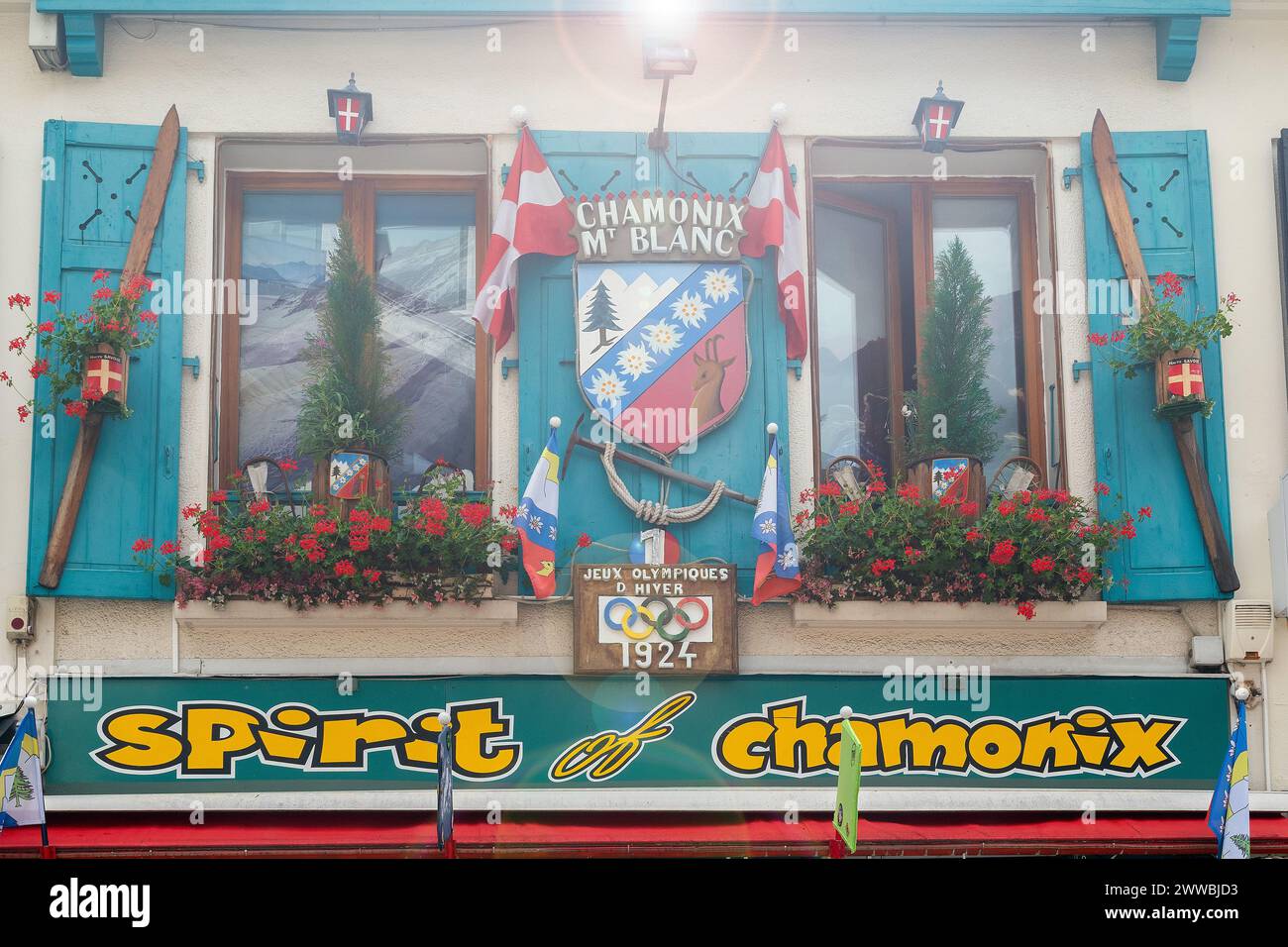 Blick von der Hintergrundbeleuchtung mit den Linsen des Schildes eines Ski- und Bergsportgeschäfts, dekoriert mit Fahnen und Holzskier im Zentrum von Chamonix, Frankreich Stockfoto