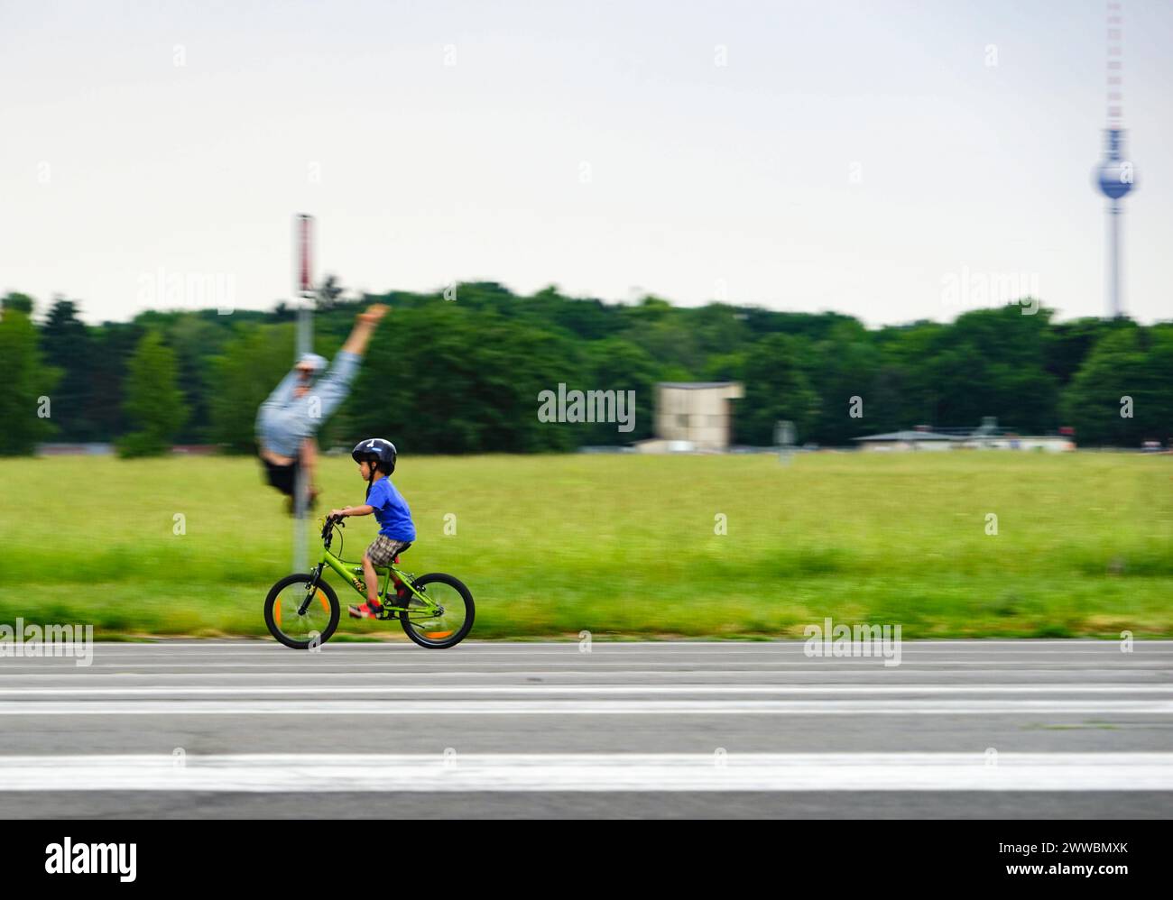 Freizeitreisende im Tempelhofer Freiheitspark Berlin - ehemaliger Flughafen mit Fernsehturmkulisse. Lustiger Pole Dance. Stockfoto