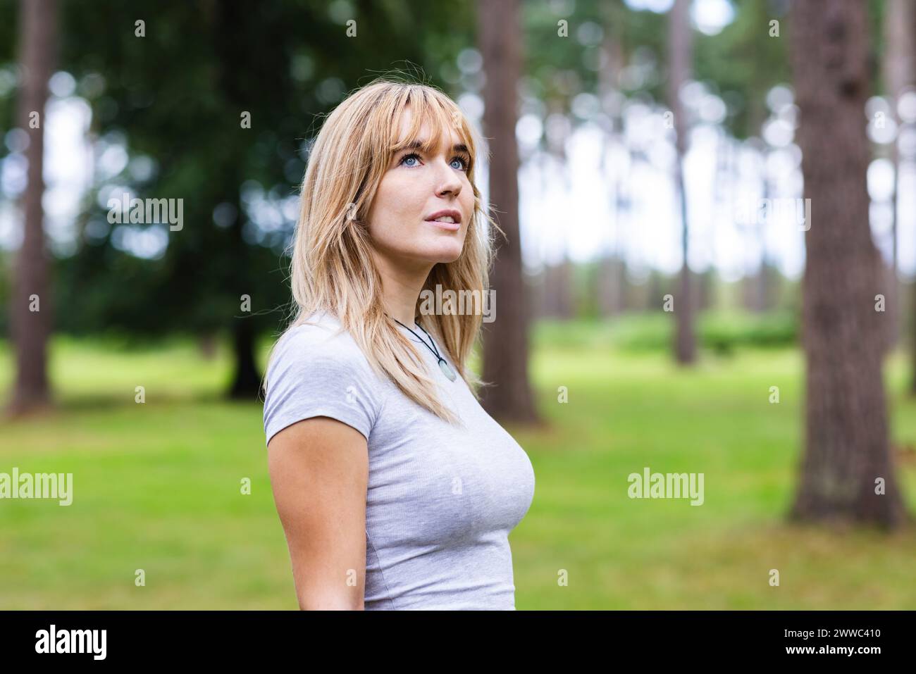 Lächelnde, schöne blonde Frau, die im Wald steht Stockfoto