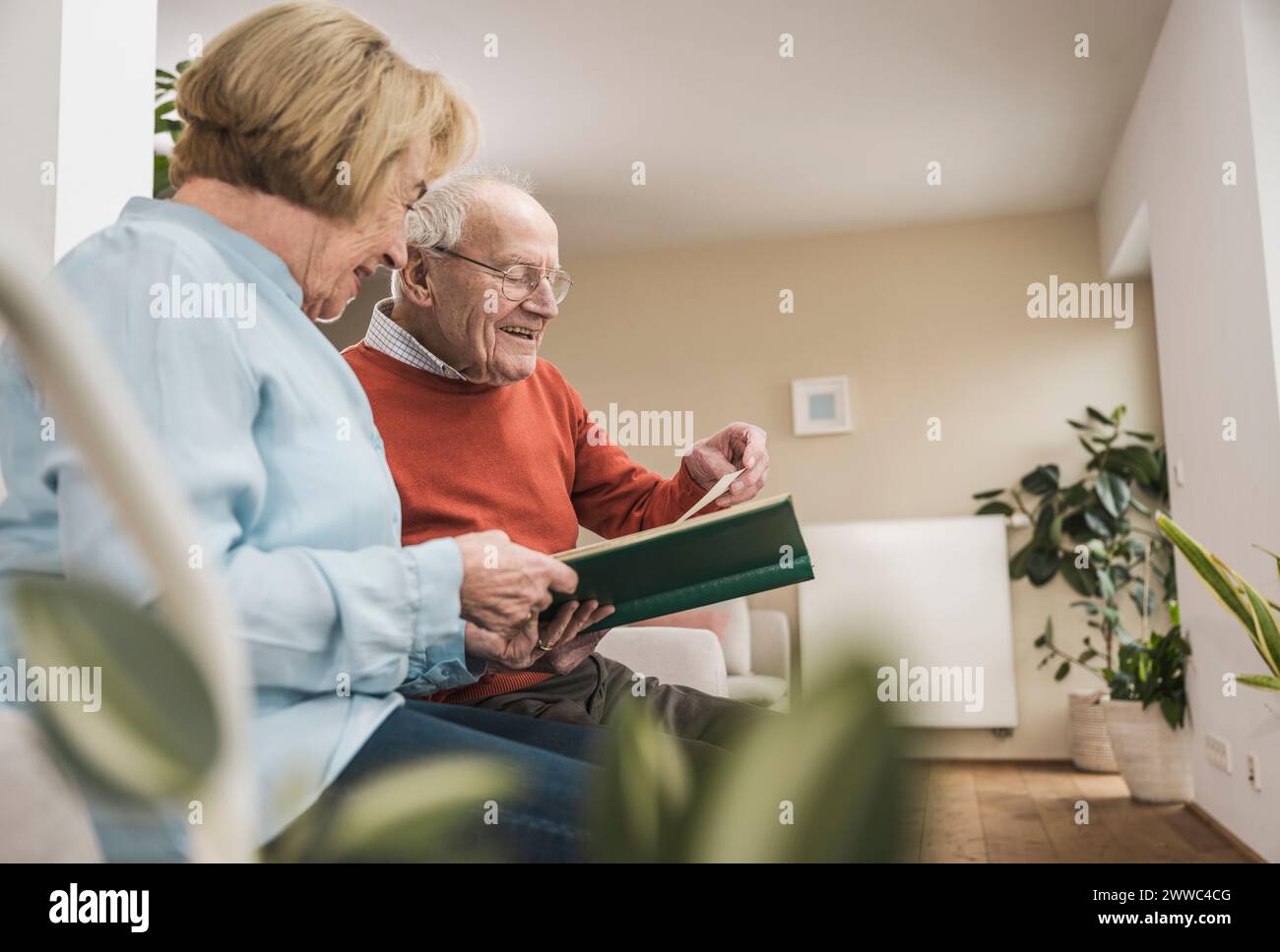 Lächelnde Seniorin und Mann, die zu Hause Fotos im Album anschauen Stockfoto