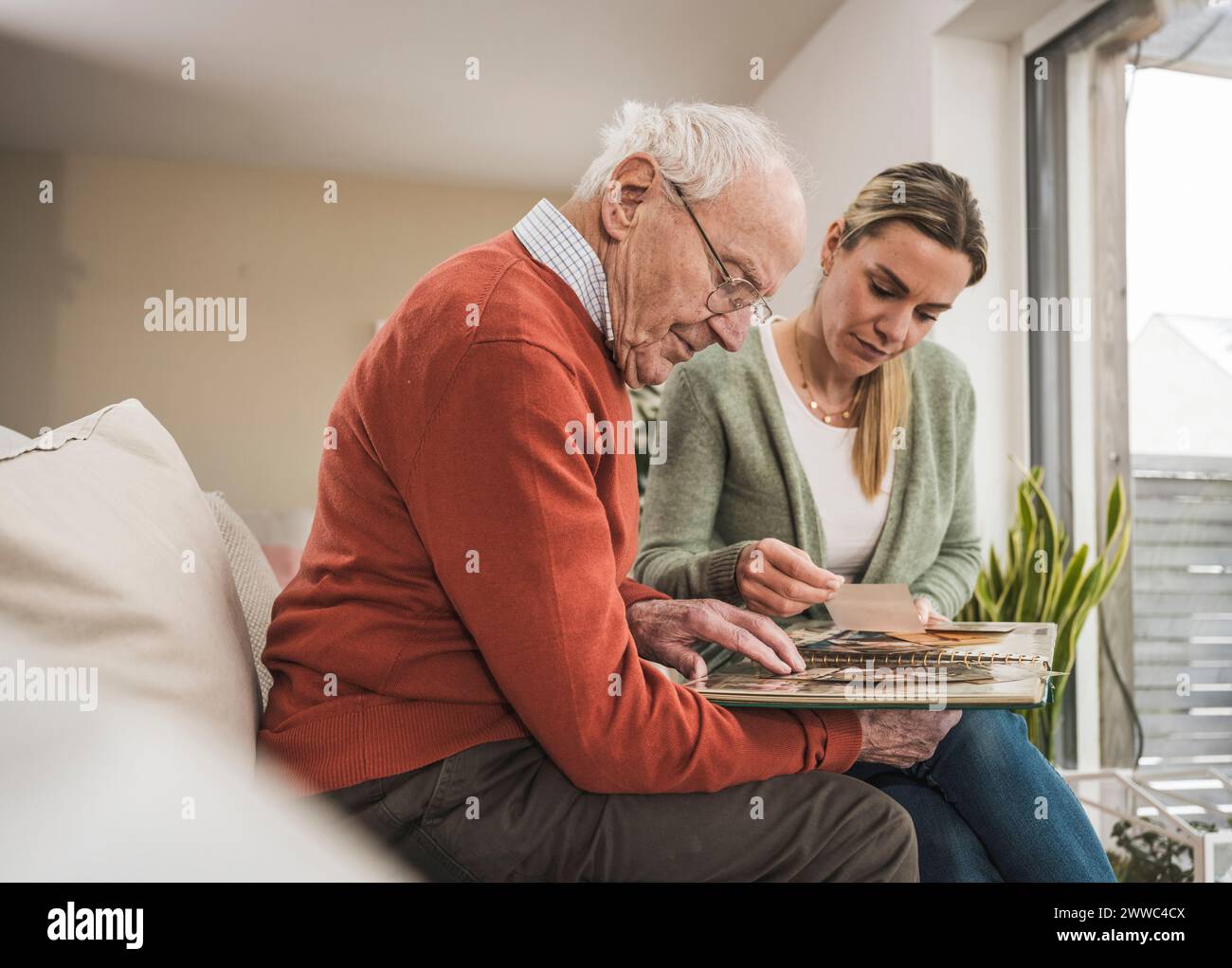Häuslicher Betreuer mit Mann, der sich das Fotoalbum anschaut Stockfoto