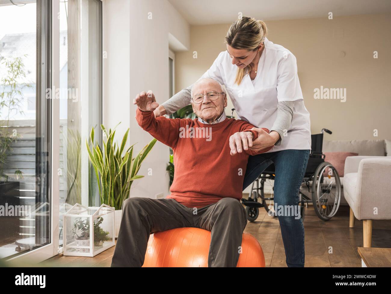 Hausbetreuer hilft Senioren beim Sport im Wohnzimmer Stockfoto