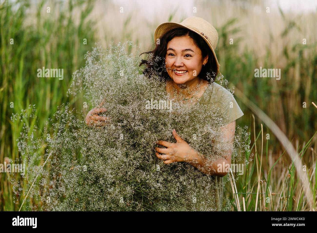 Eine verspielte Frau mit Hut und einem Haufen gypsophila-Blumen auf dem Feld Stockfoto