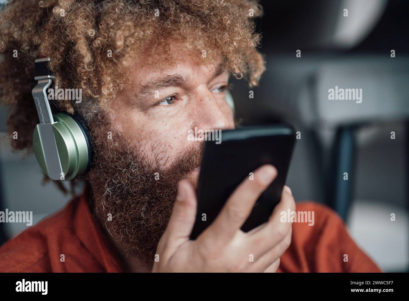 Geschäftsmann mit schnurlosen Kopfhörern und Smartphone in der Hand Stockfoto