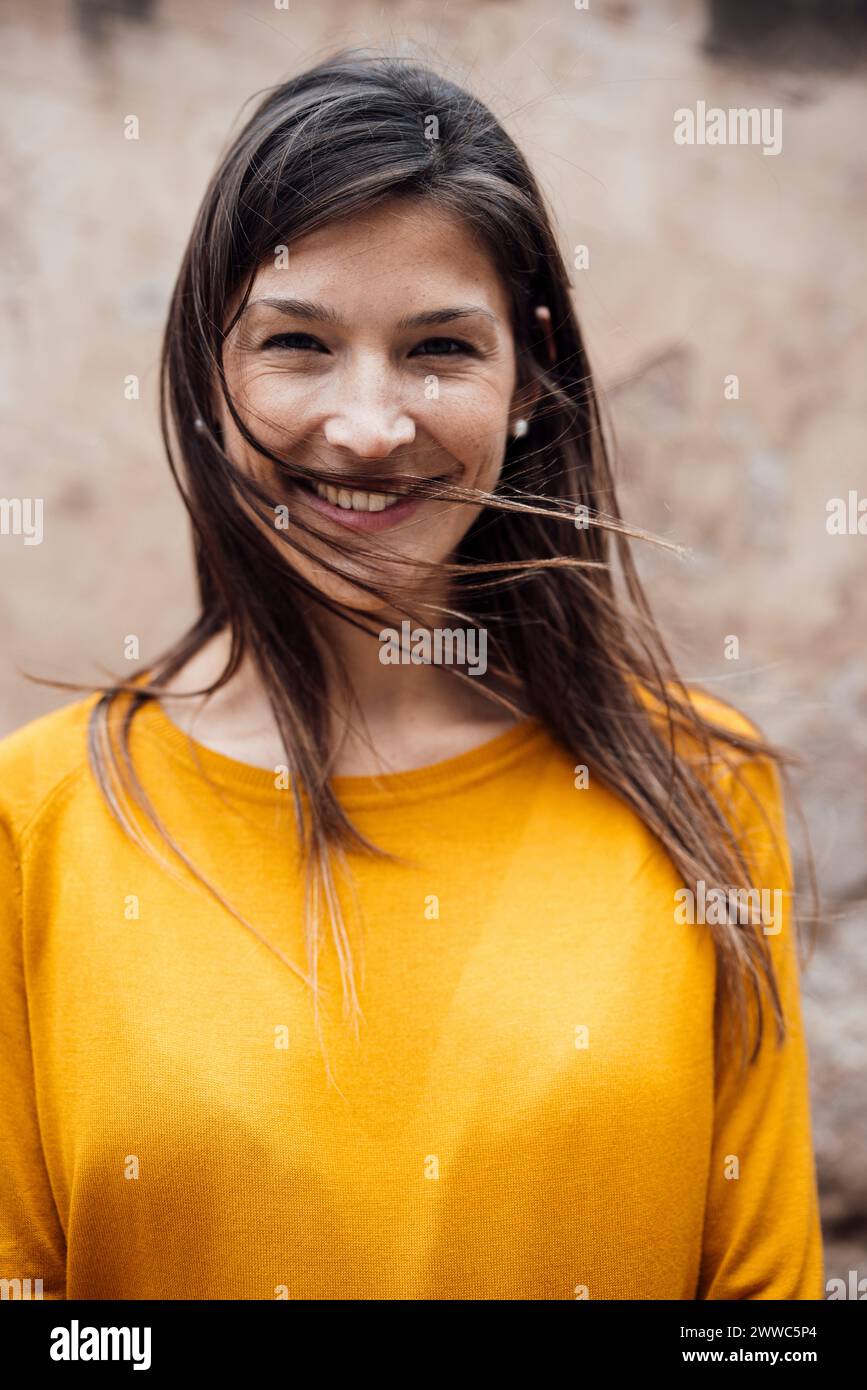 Glückliche Frau, die ein gelbes T-Shirt vor der Wand trägt Stockfoto