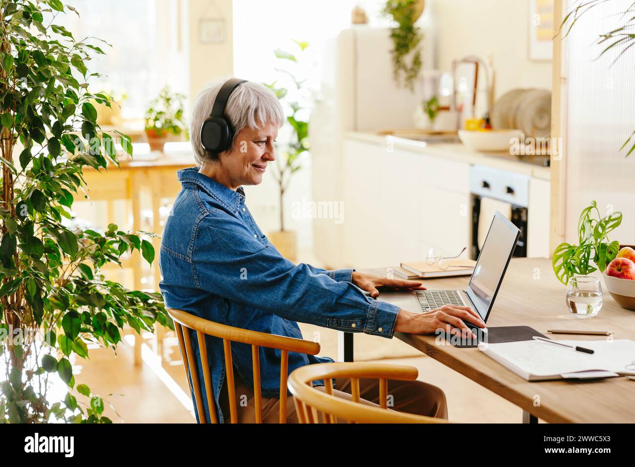 Lächelnder Freelancer mit schnurlosen Kopfhörern im Home Office Stockfoto