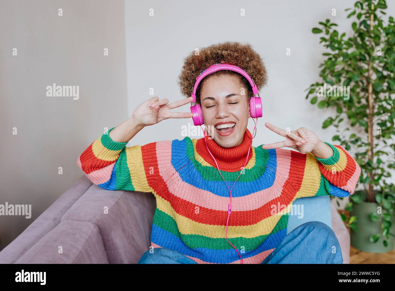 Glückliche Frau, die Musik hört und Friedenszeichen zeigt Stockfoto