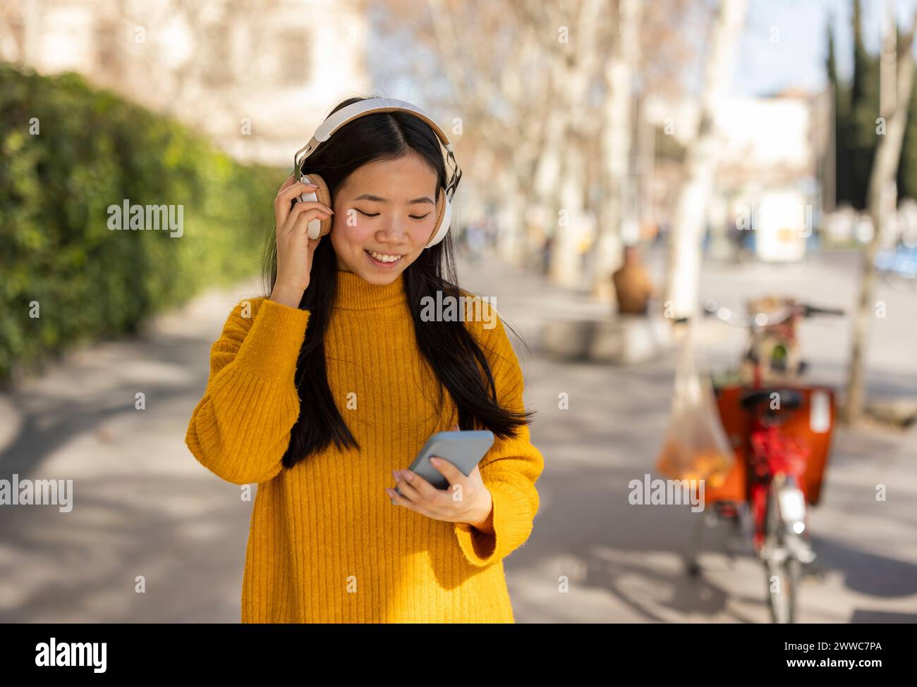 Lächelnde Frau mit schnurlosen Kopfhörern und Smartphone Stockfoto