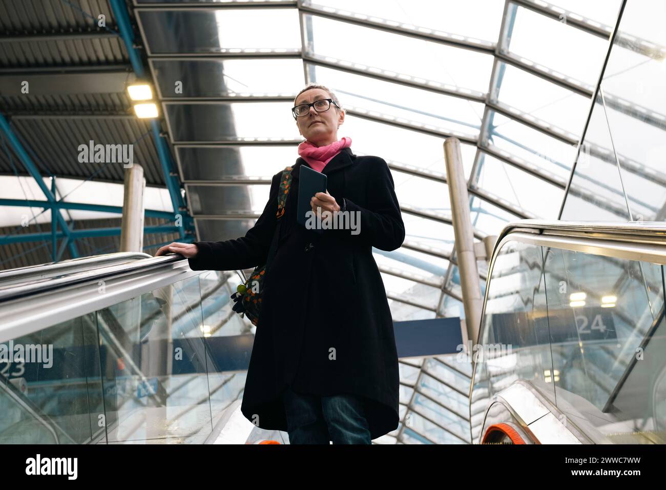 Geschäftsfrau fährt auf Rolltreppen am Bahnhof runter Stockfoto