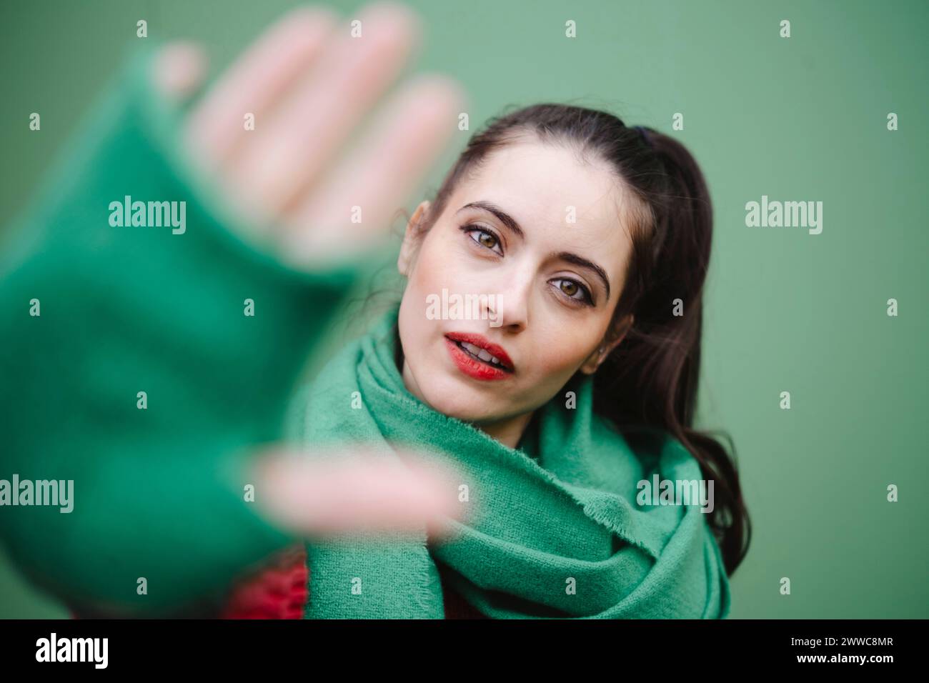 Frau zeigt Stop-Geste vor grünem Hintergrund Stockfoto
