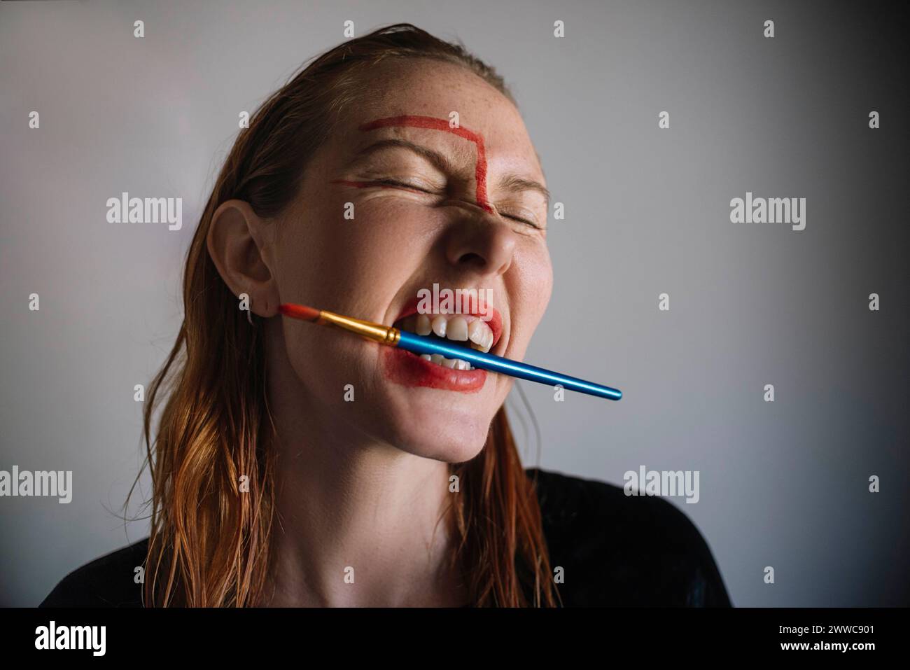 Frau mit Pinsel im Mund vor grauem Hintergrund Stockfoto