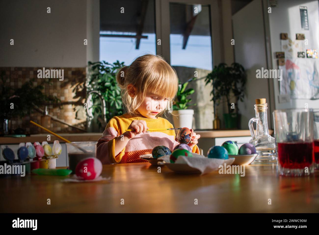 Süßes Mädchen, das zu Hause Eier für Ostern dekoriert Stockfoto