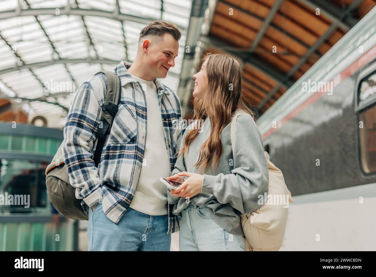 Ein junges Paar mit Rucksäcken steht am Bahnhof Stockfoto
