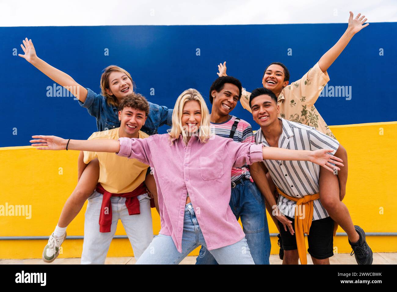 Gruppe junger Freunde mit bunten Kleidern posiert fröhlich vor der Wand Stockfoto
