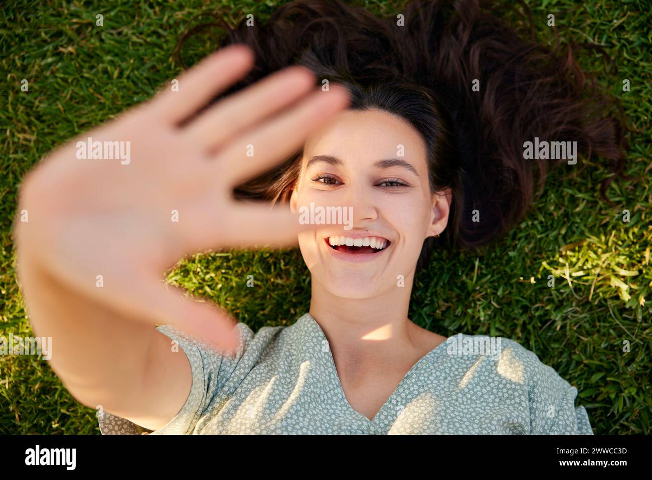 Glückliche Frau zeigt Stop-Geste und liegt auf Gras Stockfoto