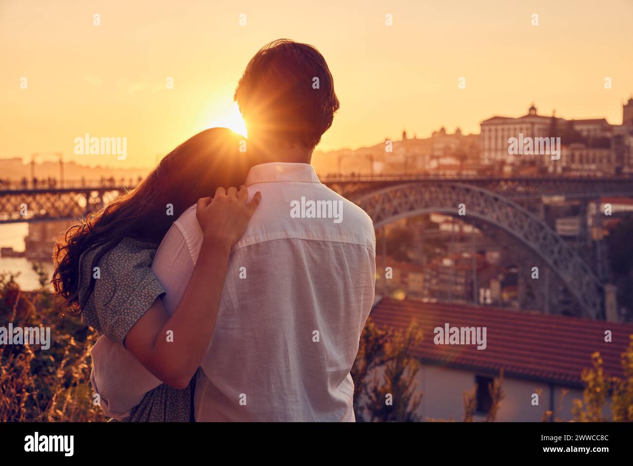 Liebevolles Paar, das sich vor der Dom Luis Brücke bei Sonnenuntergang umschließt, Porto, Portugal Stockfoto