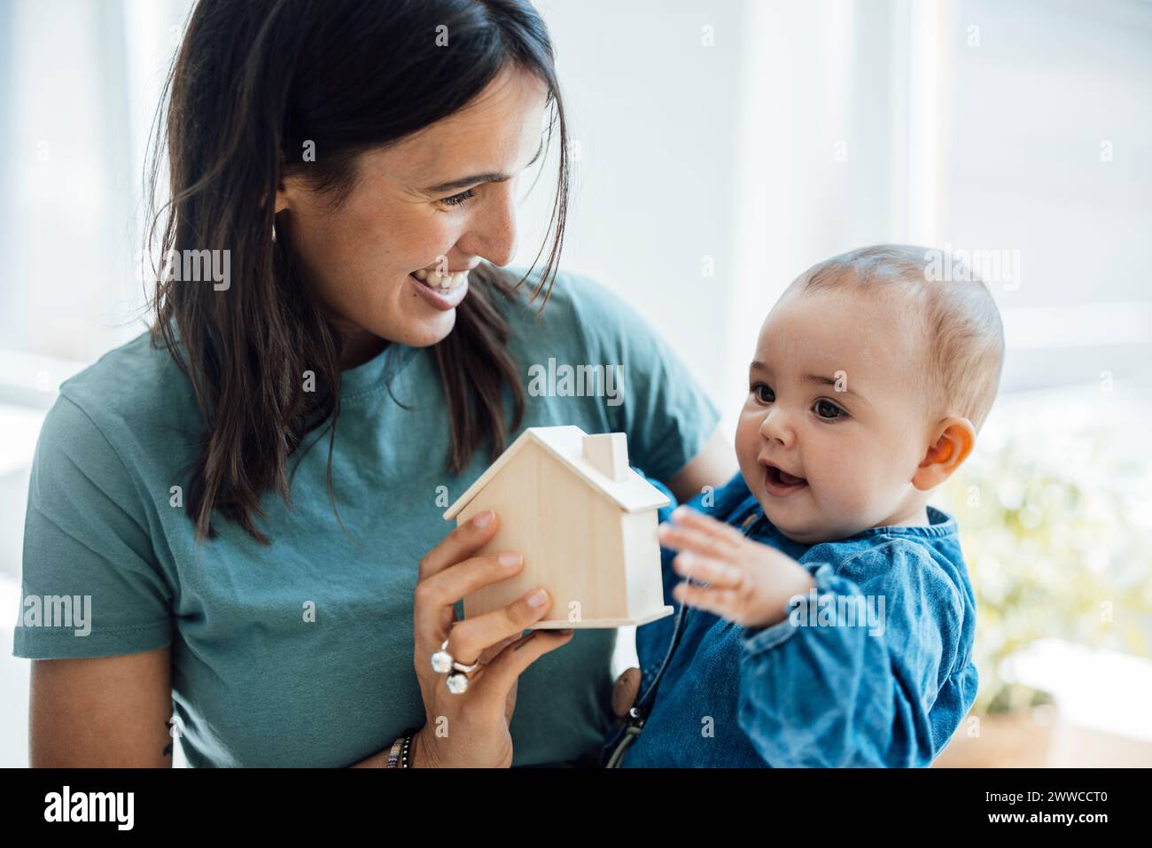 Glückliche Mutter zeigt der kleinen Tochter ein hölzernes Modell Stockfoto