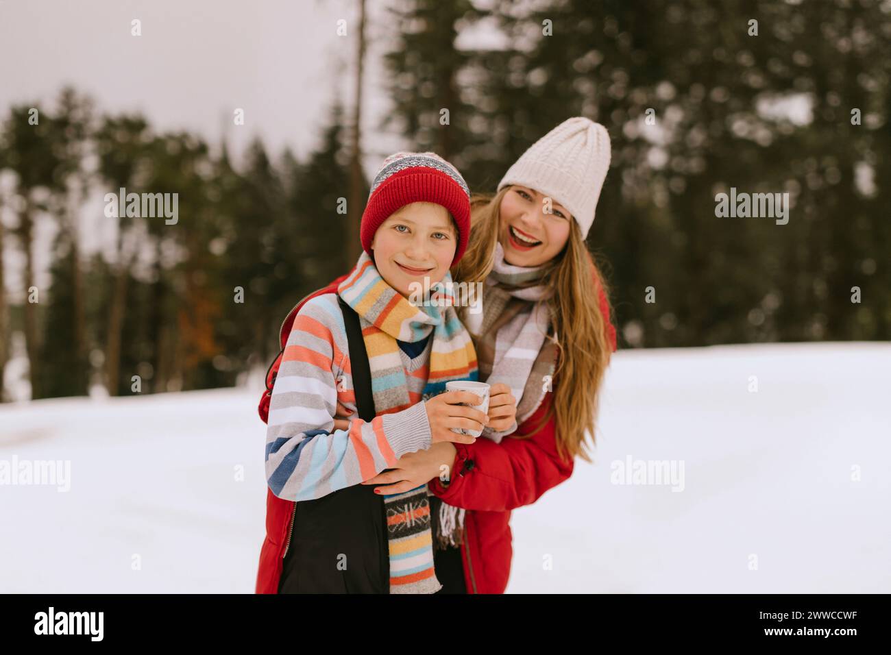 Glückliche Mutter und Sohn tragen warme Kleidung im Winterwald Stockfoto