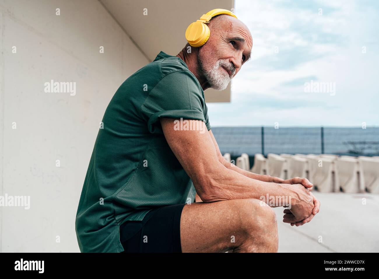 Senior-Mann, der Musik über kabellose Kopfhörer hört Stockfoto