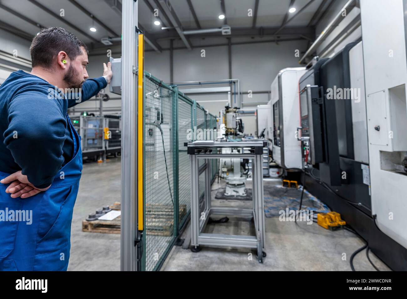 Junger Wartungstechniker, der in einer modernen Roboterfabrik arbeitet Stockfoto