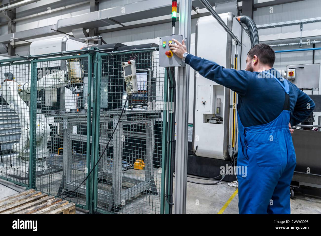 Junger Wartungstechniker, der mit Roboterarm in modernen Fabriken arbeitet Stockfoto