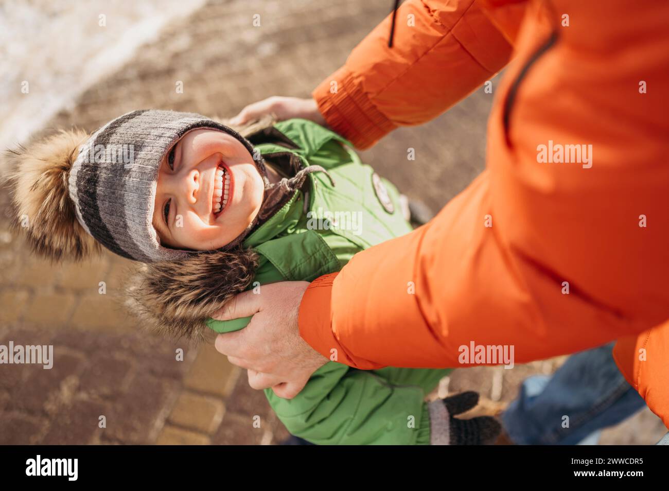 Lächelnder Junge im Parka-Mantel, der im Winter mit dem Vater steht Stockfoto