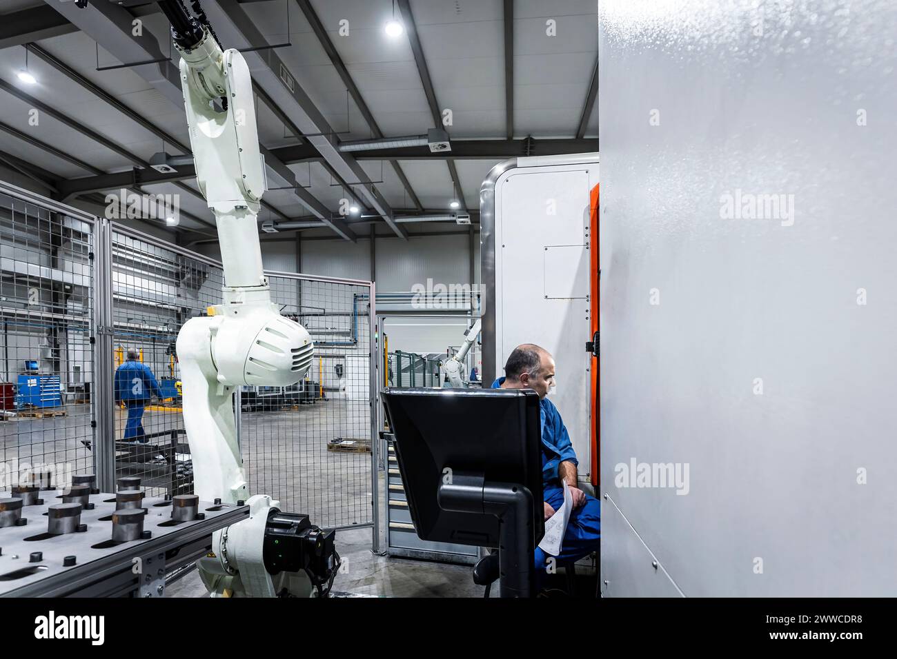 Wartungstechniker, der CNC-Maschine mit Roboterarm bedient Stockfoto