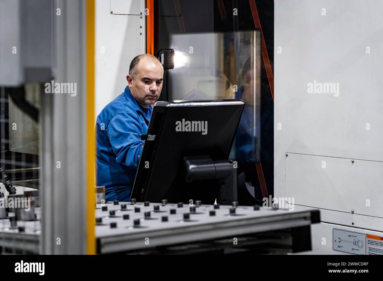 Wartungstechniker, der die CNC-Maschine in einem modernen Werk bedient Stockfoto