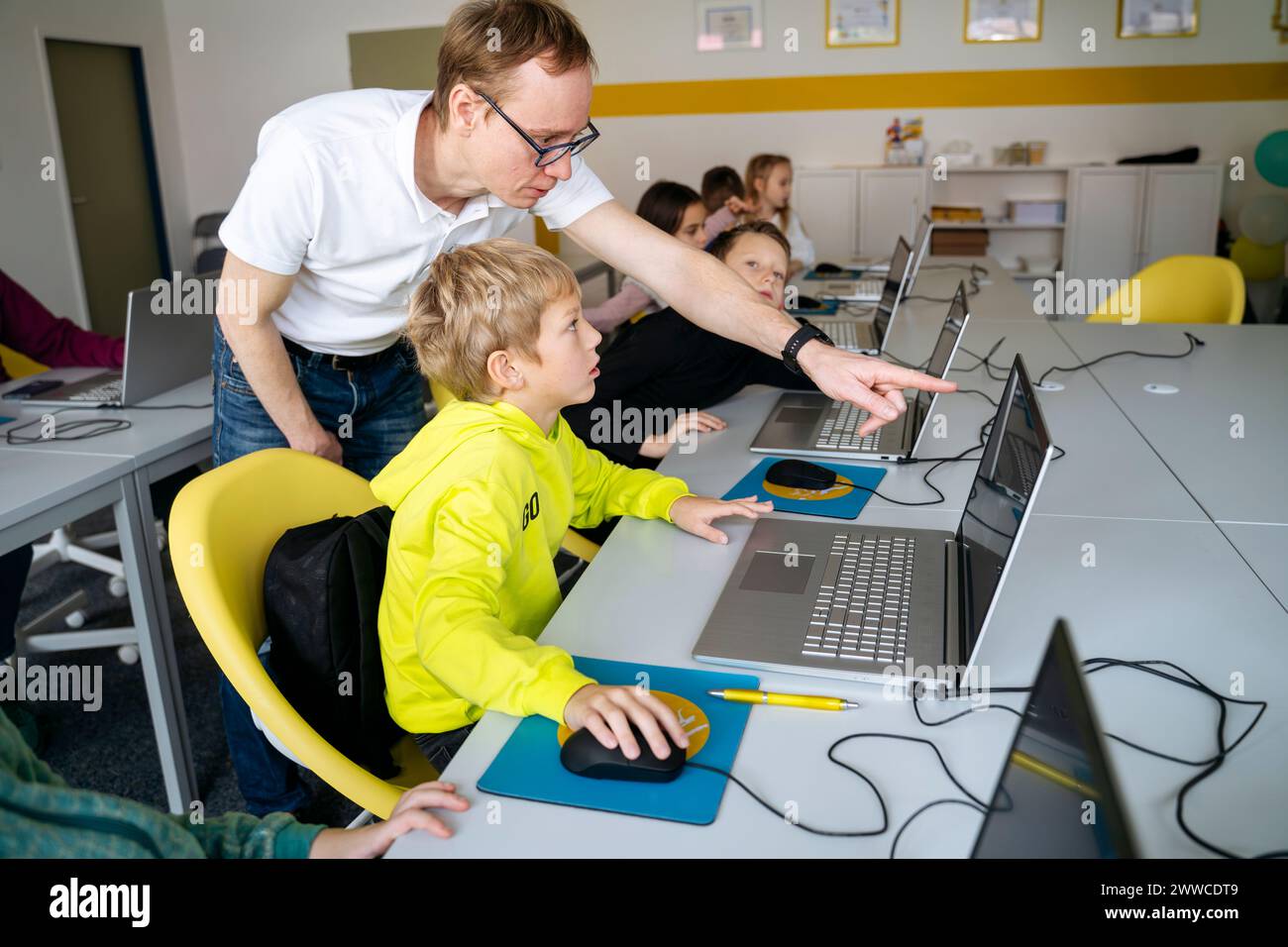 Professor zeigt auf Laptop und unterrichtet Boy Coding im Klassenzimmer Stockfoto