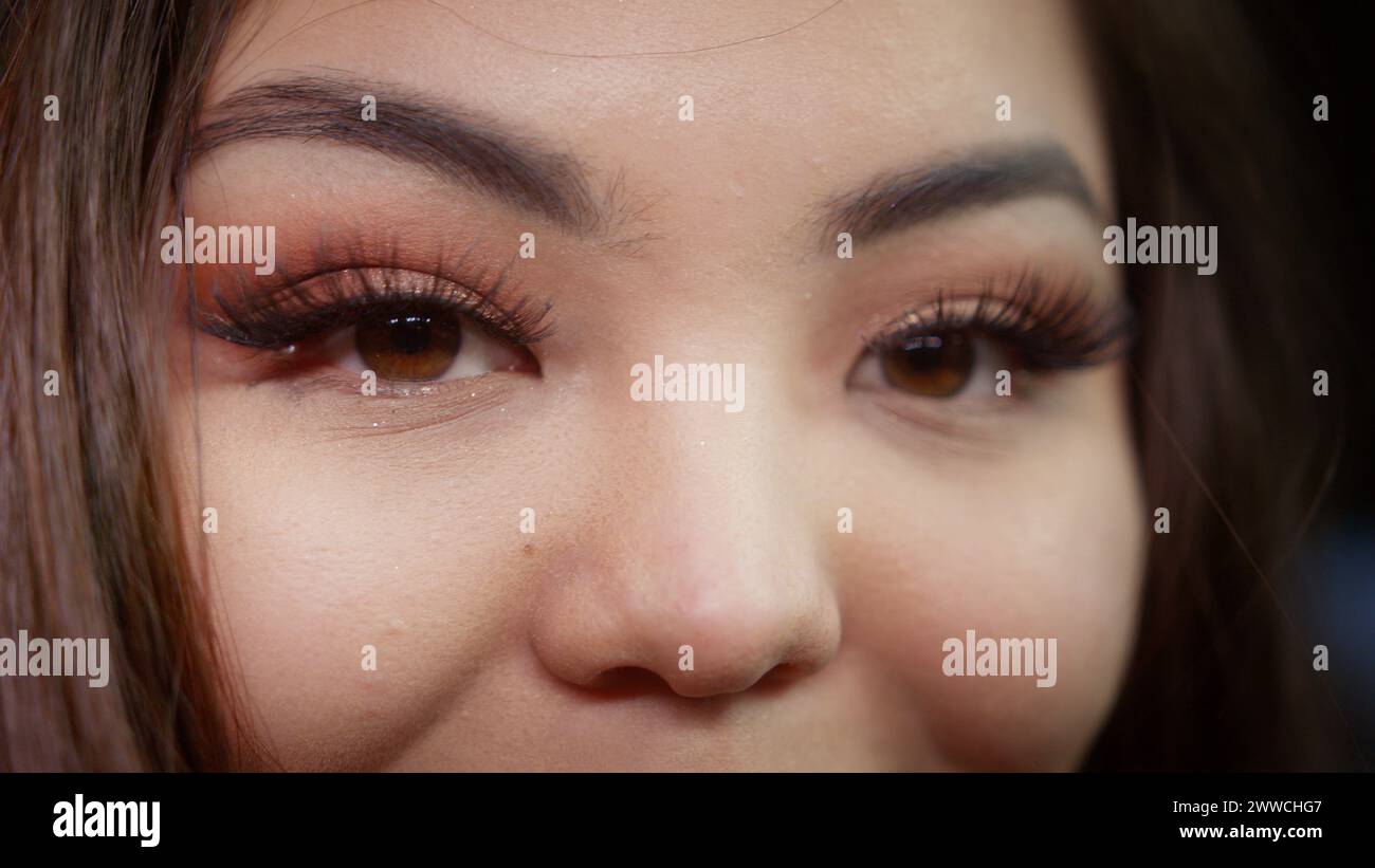 Extreme Nahaugen einer asiatischen Frau mit langen Wimpern, die in die Kamera schaut Stockfoto