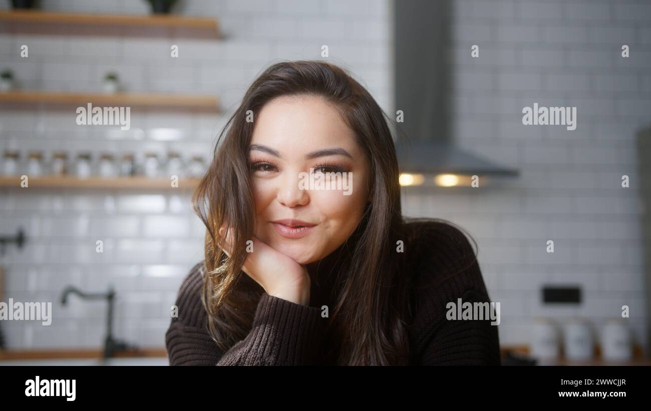 Porträt einer schönen asiatischen Frau, die in die Kamera schaut und in der modernen Küche zu Hause lächelt. Mittlere Nahaufnahme Stockfoto