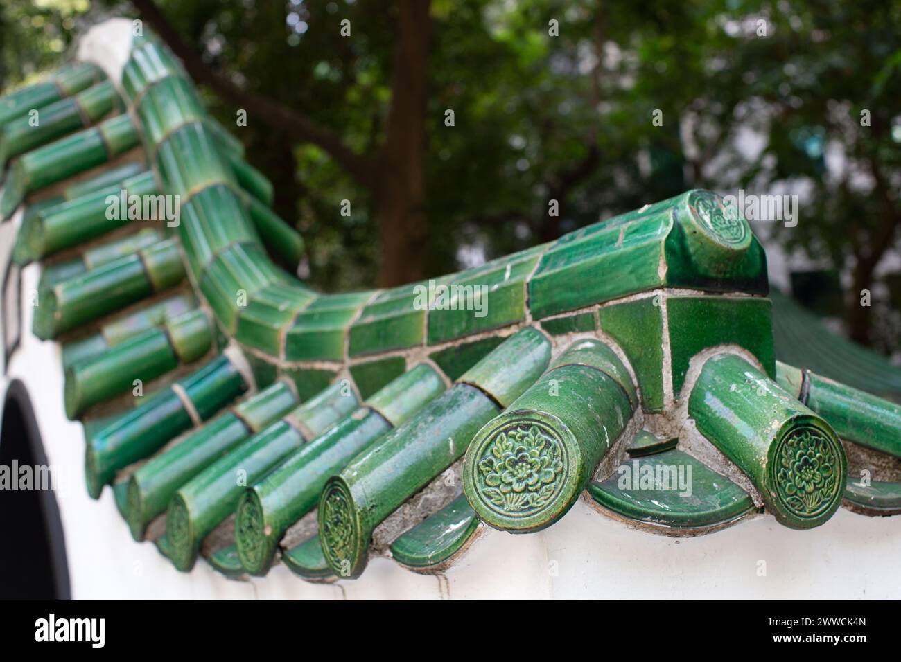 Die Kurve und die Speichen grüner Fliesen entlang einer Wand ähneln einem Tausendfüßler. Stockfoto